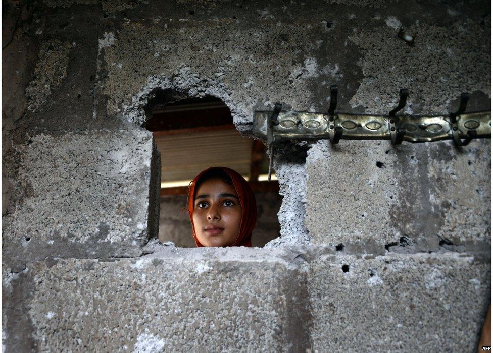 A Pakistani Kashmiri, affected by cross border firing, shows the damaged wall hit by mortar shell at her home in Dhair Bazar, Madarpur sector on the on the Line of Control (LoC), some 150 kilometres from Muzaffarabad, capital of Pakistan administered Kashmir on 8 August 2015.