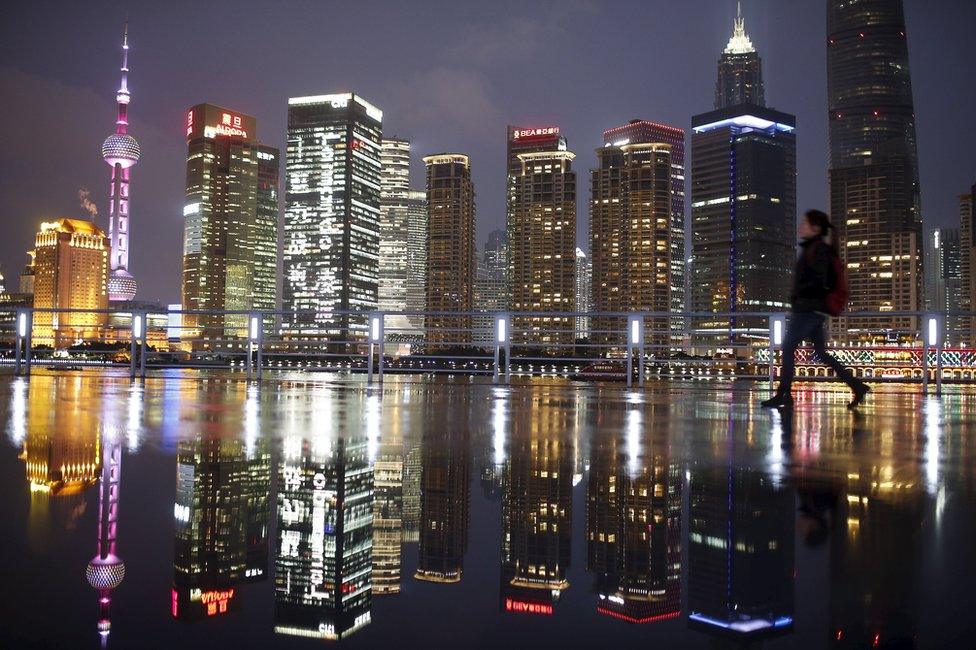 A woman walks at the Bund in front of the financial district of Pudong in Shanghai in this 5 March 2015 file picture