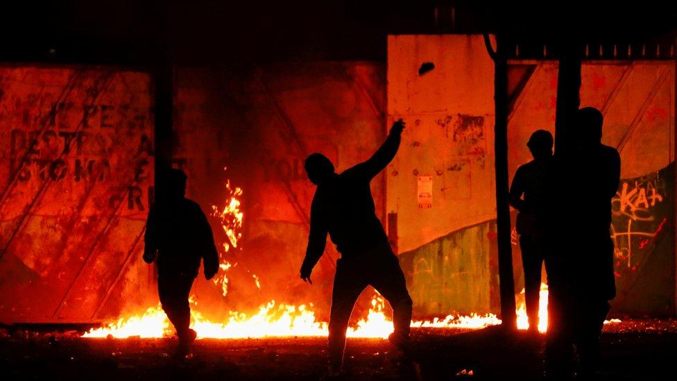 Rioters are seen at the "peace wall" gate into Lanark Way as protests continue in Belfast,