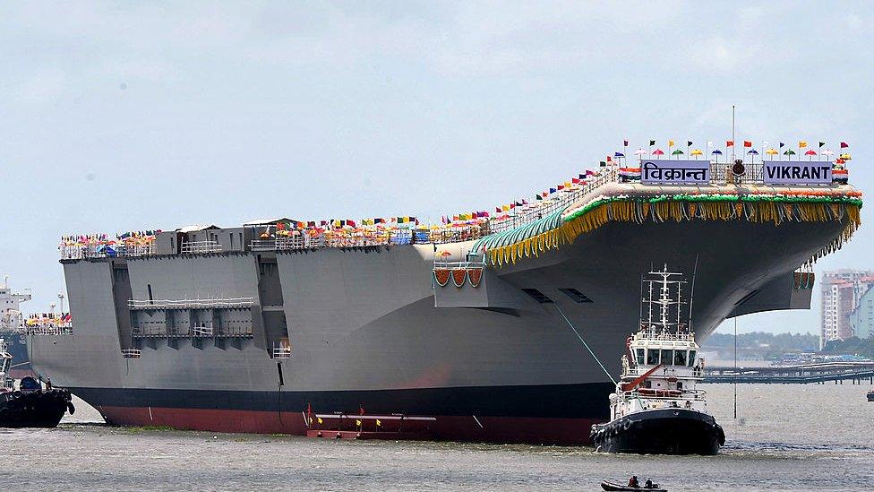 Tugboats guide the indigenously-built aircraft carrier INS Vikrant as it leaves the dock of the Cochin Shipyard after the launch ceremony in Kochi on August 12, 2013.