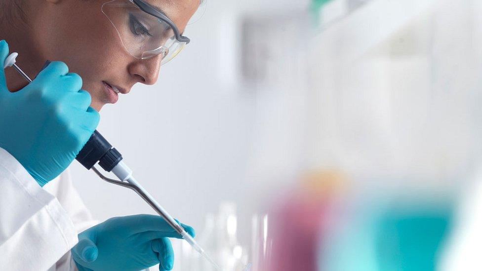 researcher in goggles and gloves with pipette