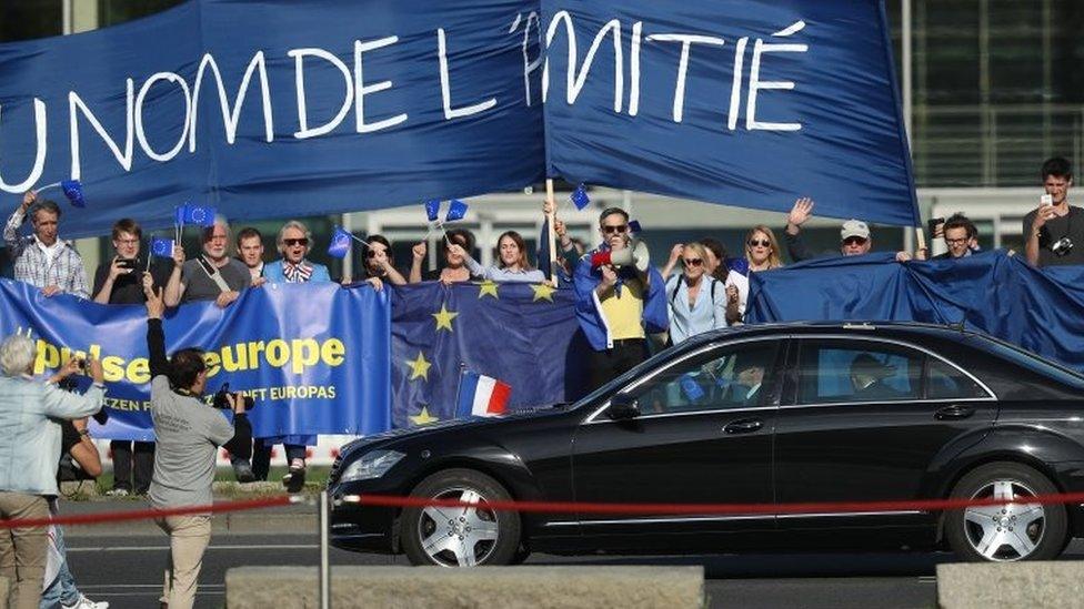 The car carrying newly-elected French President Emmanuel Macron drives past pro-European supporters as Macron arrives to meet German Chancellor Angela Merkel chat the Chancellery on May 15, 2017 in Berlin, Germany.