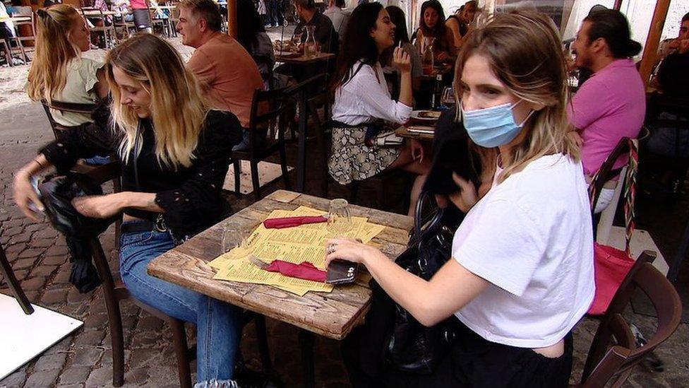 Busy restaurant with mask-wearer and screen