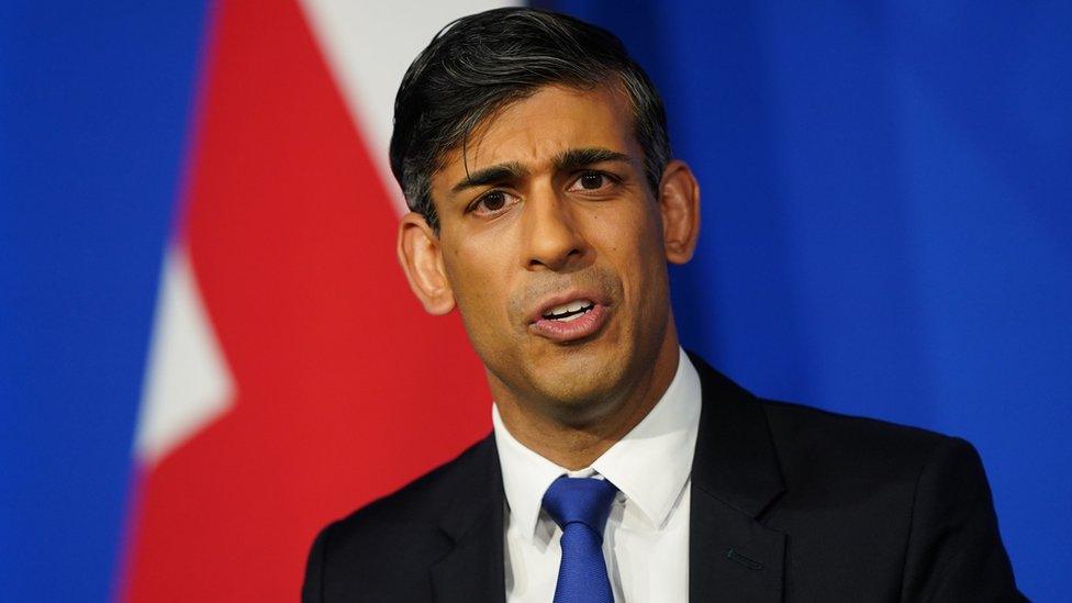 PM Rishi Sunak speaks in front of a UK flag