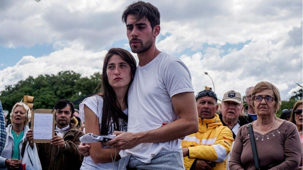 A woman and man holding each other in a crowd