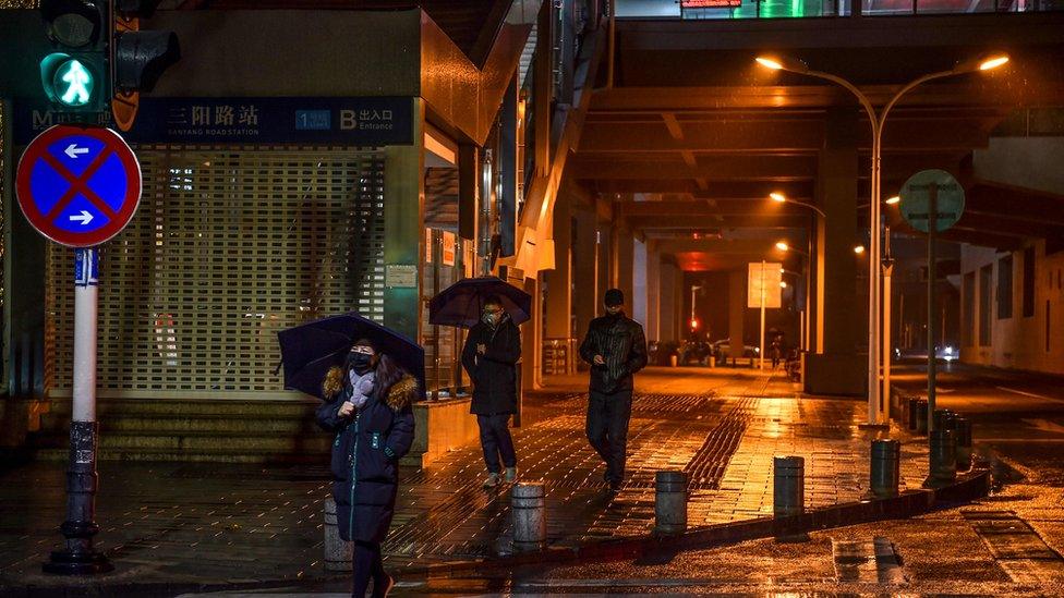 People in protective masks walk on a street in Wuhan