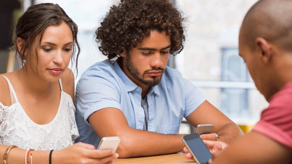 People sitting together and looking at their phones