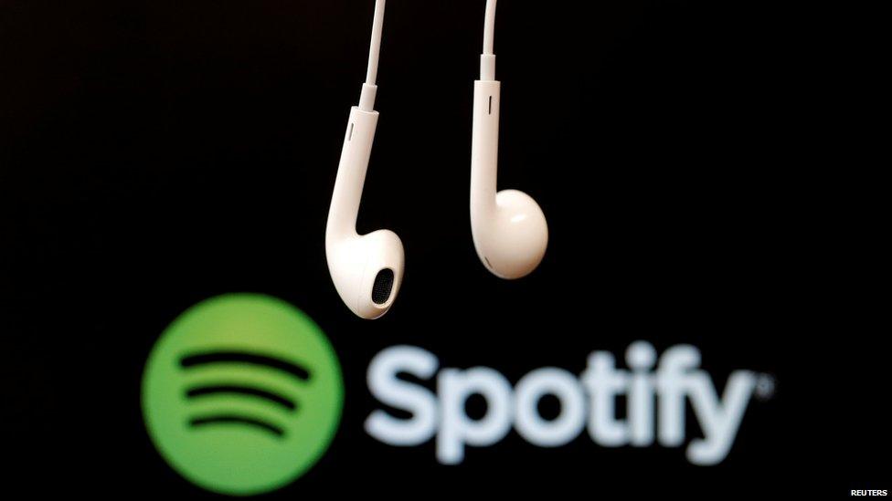 A pair of headphones in front of the spotify logo