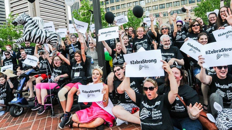 A group of EDS sufferers and supporters hold 'zebra strong' plaques