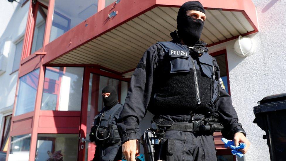 German police leave a building in a raid at Maintal, south of Frankfurt on 18 April