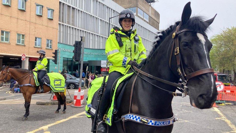 A female police officer sits on a black horse outside the Bristol Royal Infirmary