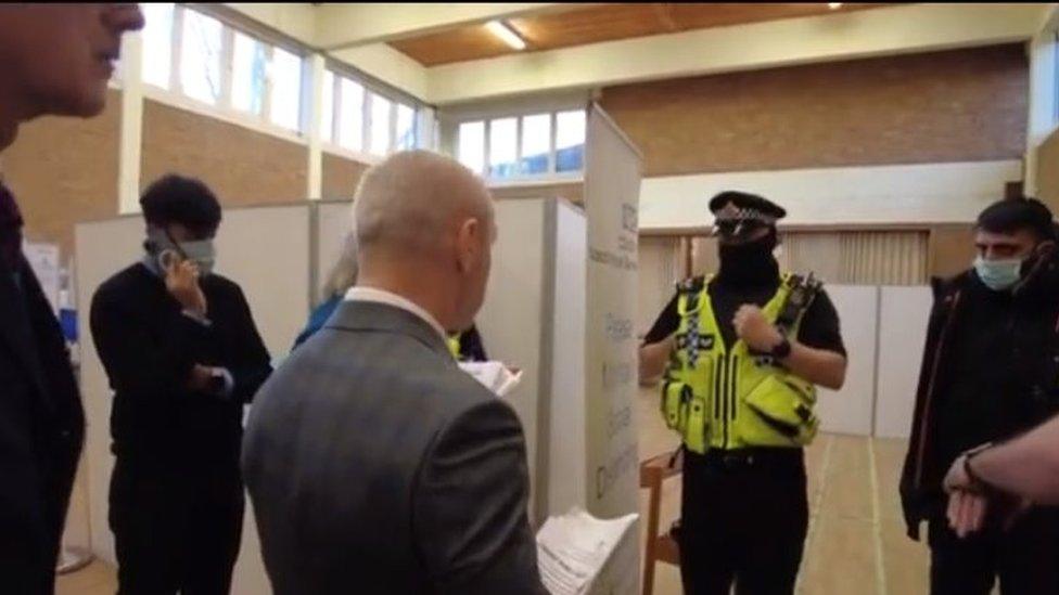 Protesters talking to police at a vaccination centre in Stockport