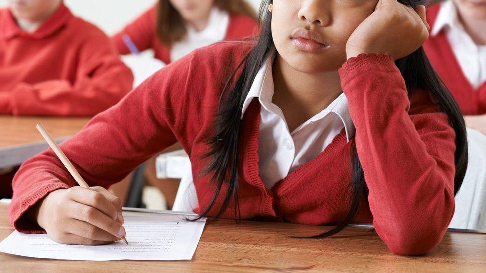 Stock image of a student writing with head in hands