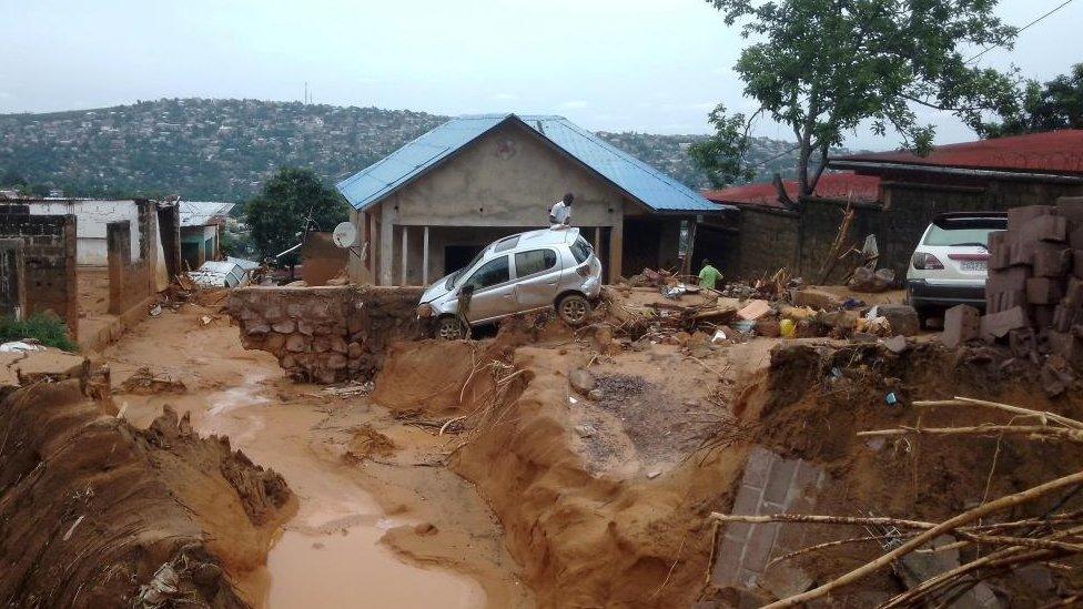 A man walks past a car stuck in the mud after heavy rains in Kinshasa, Democratic Republic of Congo