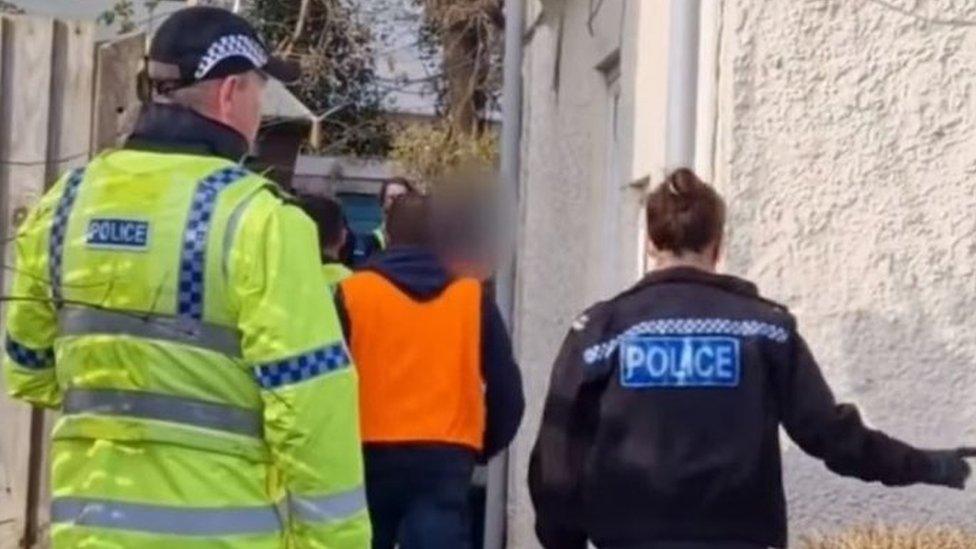 Police officers outside a home from which they are seizing drugs or illegal substances