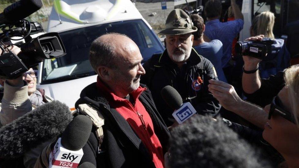 Journalists surround a tourist who was trapped overnight in cable cars which got stuck above the Alps (09 September 2016)