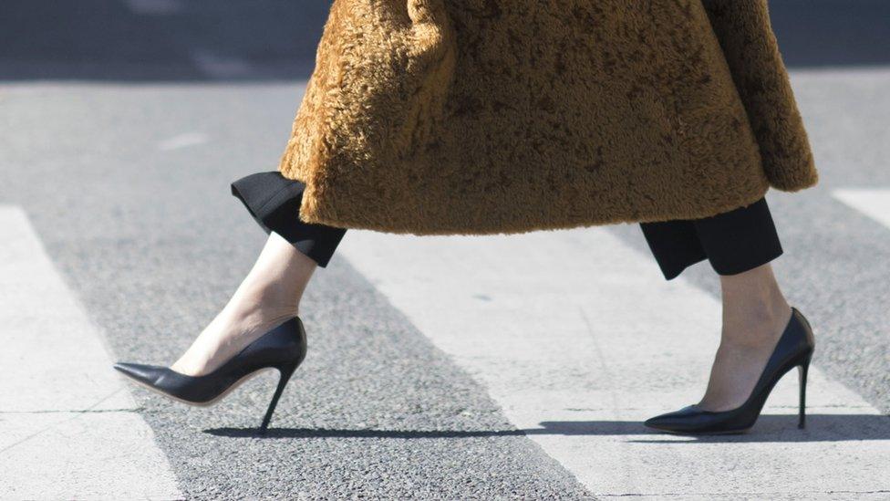 A woman crossing a street in heels