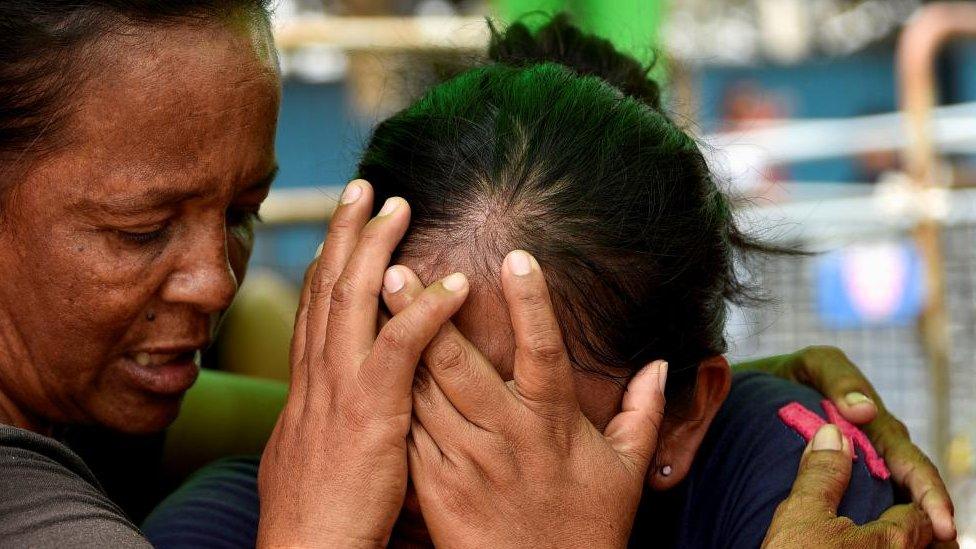 The relative of an inmate reacts while another person tries to comfort her as she waits for news about their loved ones outside the prison in Guayaquil