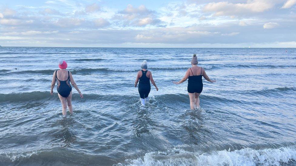 Swimmers walk into the sea at Helen's Bay.