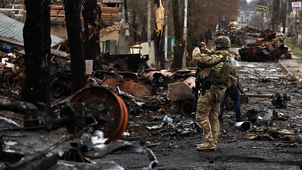 A Ukrainian soldier with a destroyed Russian tank and armoured vehicles in Bucha