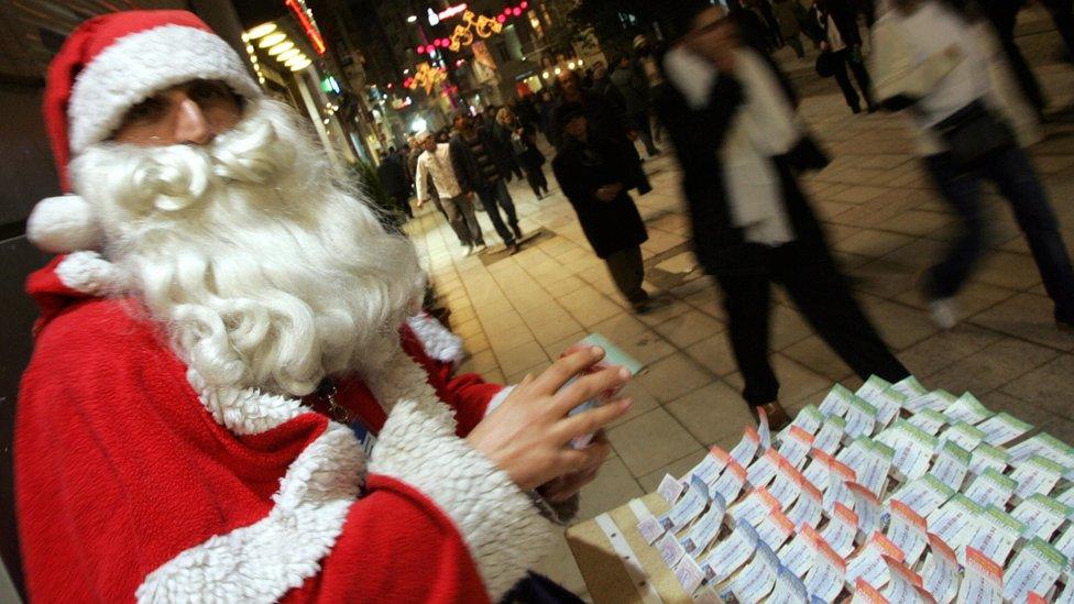 A man in a Santa suit selling lottery tickets