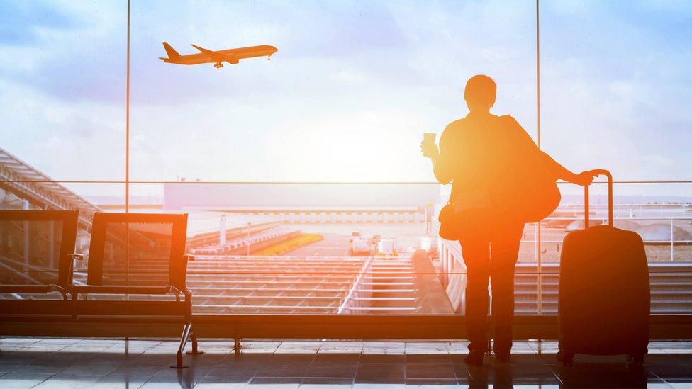 traveller watching a flight take off at n airport departure lounge