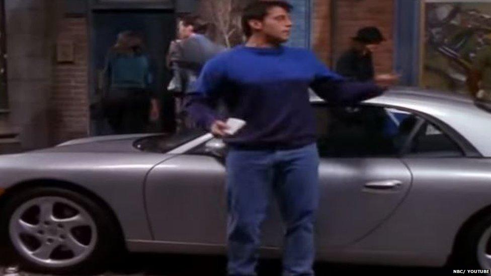 Joey standing next to a Porsche.