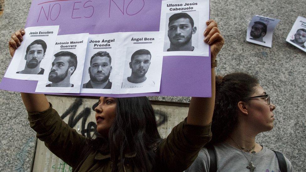 A woman holds aloft a poster during a demonstration - on it are the photographs of the "wolf pack" with the Spanish words for "no is no"