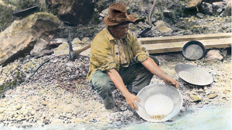 A prospector pans for gold in northern California. Hand tinted photograph, circa 1890.