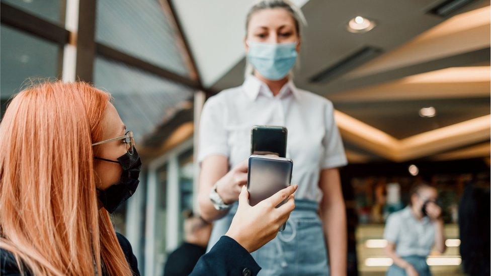 A waitress scans a Covid pass