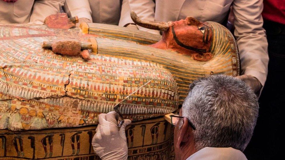 An-expert-closely-studies-a-sarcophagus