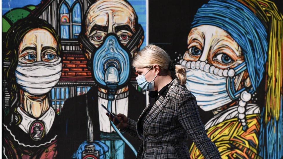 Members of the public walk past coronavirus posters in the Merchant City on September 18, 2020 in Glasgow,