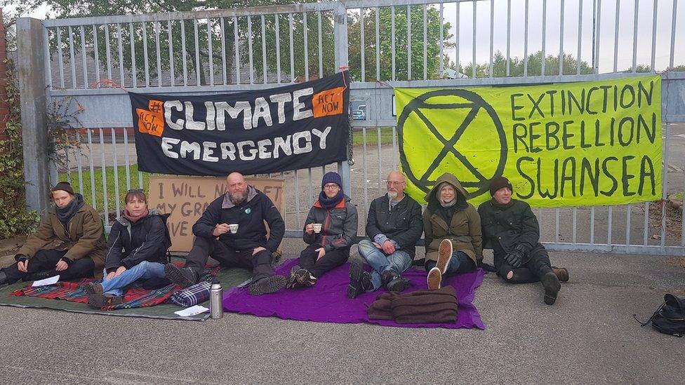 Protestors sit outside the gates