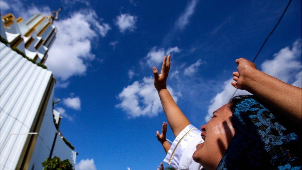 A woman raises her hand to the sky at the annual gathering of the Light of the World church.