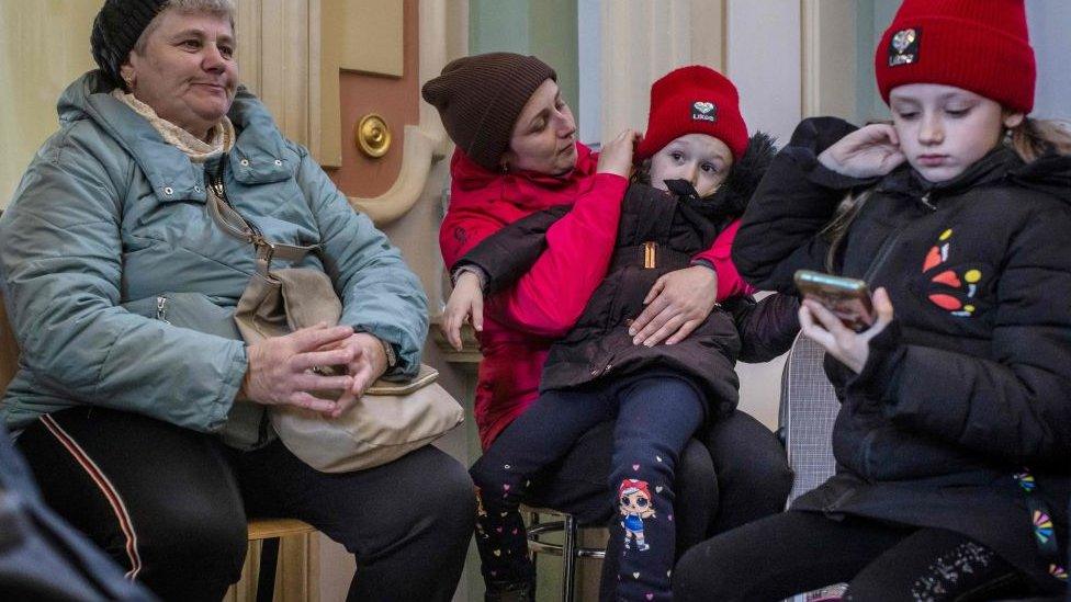 Two women and two girls wait for a train