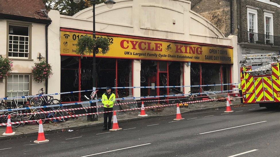 Policeman stands outside a burnt-out shop in Bury St Edmunds.