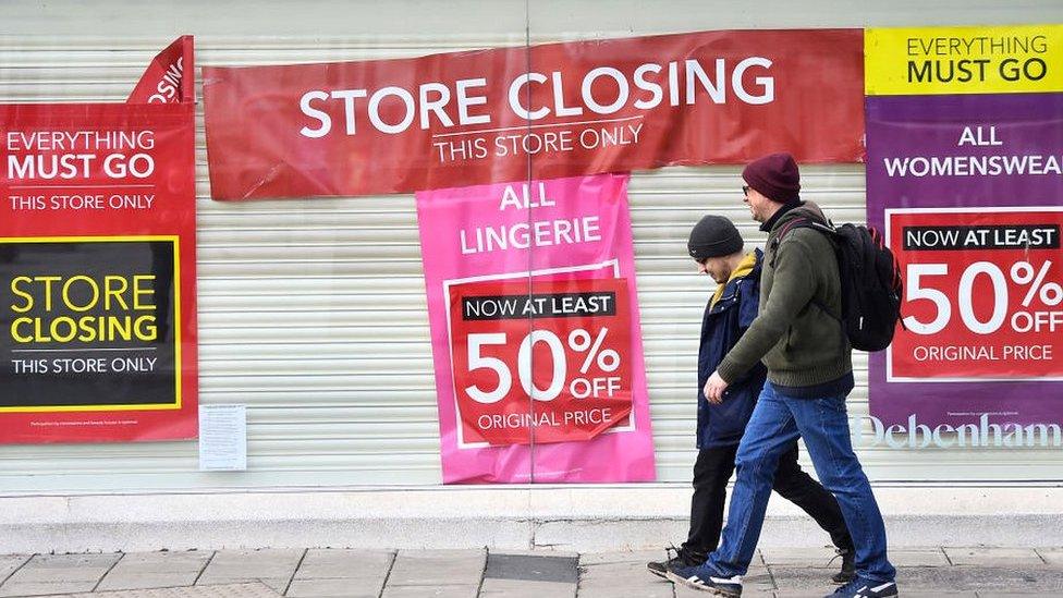 People walk by closed Debenhams shop