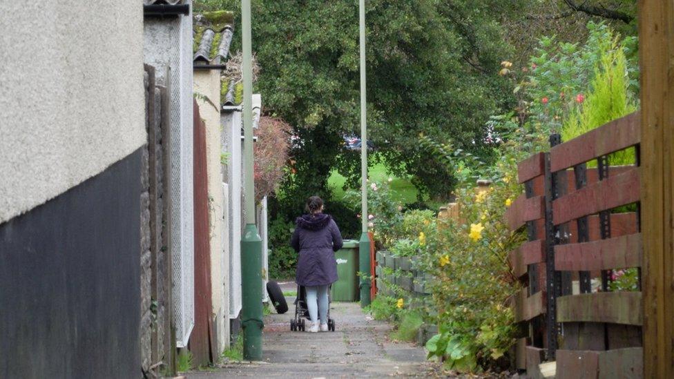 A mother pushes a baby down the rows of houses in Trevelyan Court, Lansbury Park