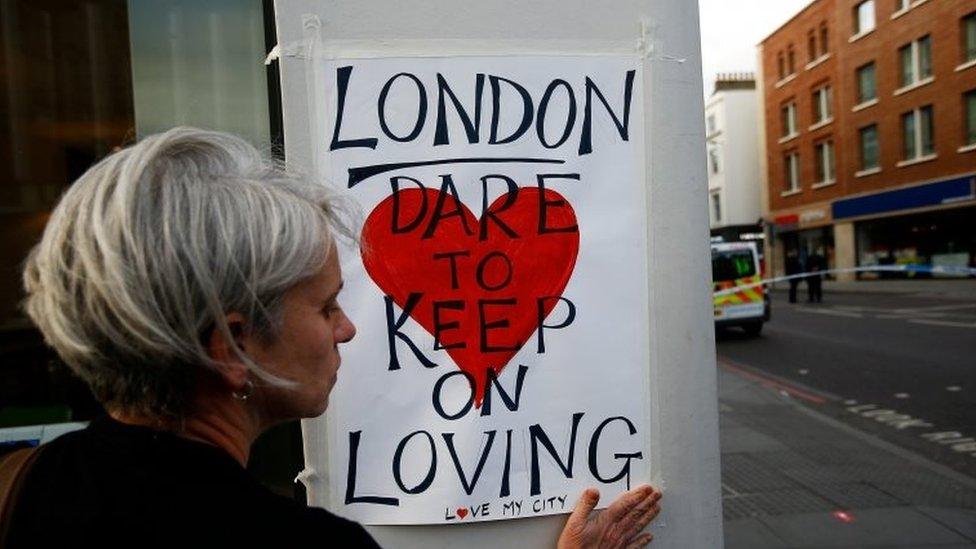 A woman attaches a sign near London Bridge in London