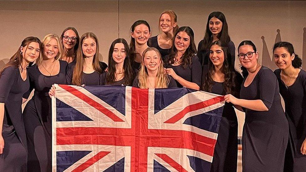 Amabile choir from Merchant Taylors' School holding a Union Jack flag