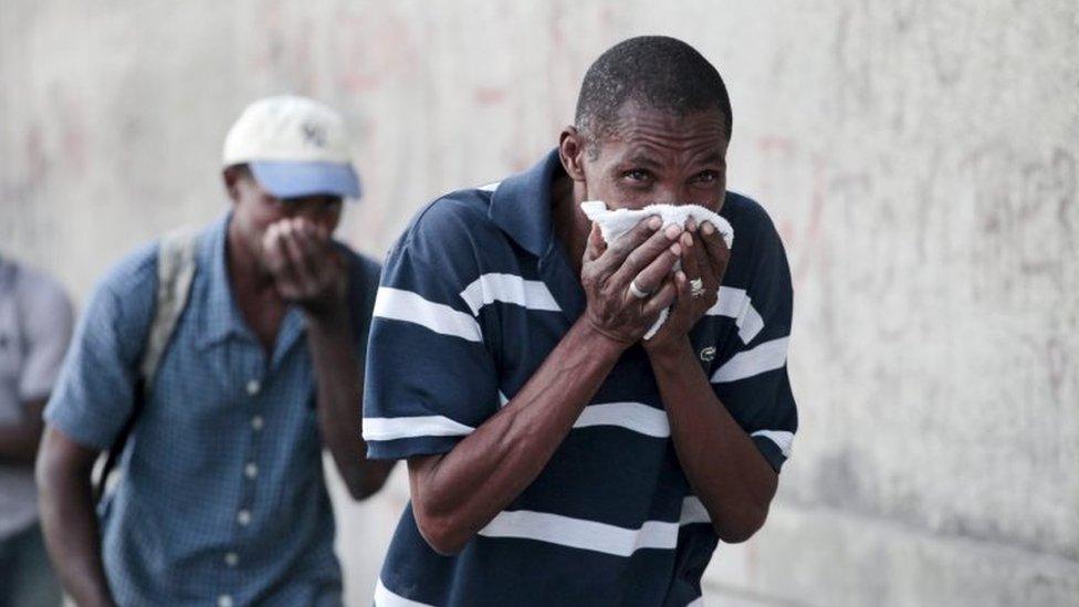 A man covers his face to protect himself from tear gas after clashes between residents and protesters in a demonstration against the results of the presidential elections in Port-au-Prince on 24 November, 2015