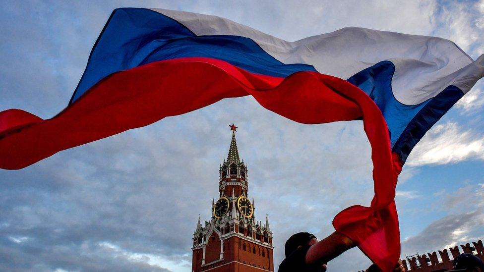 A Russia fan waves the Russian national flag as fans celebrate at the Red Square in Moscow