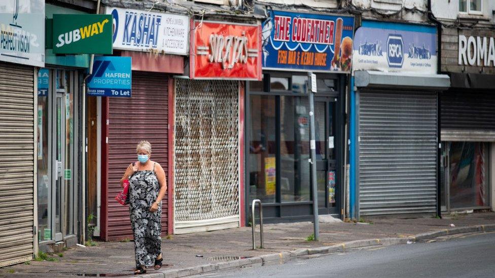 A woman walking along Cardiff street with closed shops behind