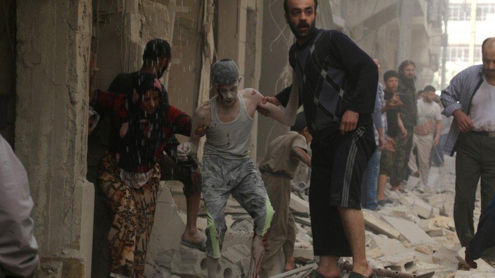 Syrians help a wounded youth following an air strike on the Fardous rebel held neighbourhood of the northern Syrian city of Aleppo