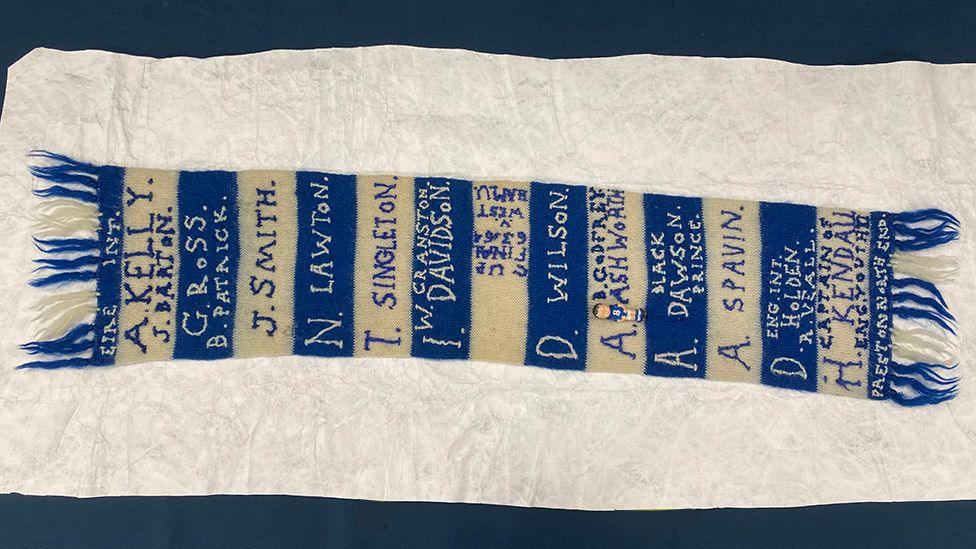The 1964 scarf, with blue and white stripe and fringes and names sewn over the stripes