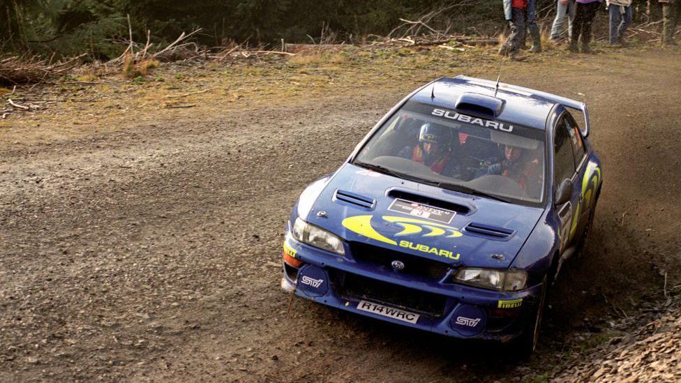 Blue Subaru car skidding on a gravel track