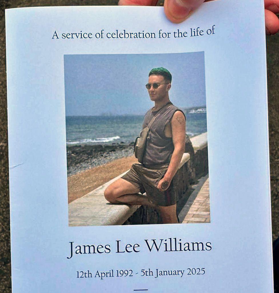 The cover of the oder of service showing a photo of Williams with green hair wearing shorts and short sleeves, by the sea in the sun resting one knee  against a wall