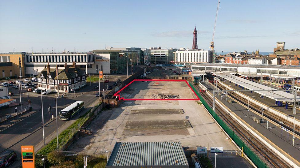 Demolished site set for an office block highlighted in red which is next to Blackpool North railway station with Blackpool Tower in the background