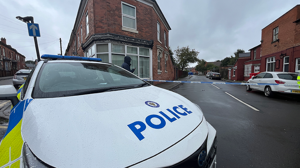 Police at the scene of an incident in the area, with police tape and a police car blocking the street