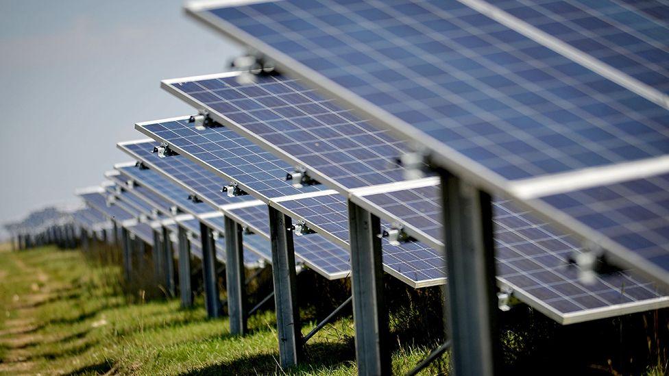 Close up of a row of solar panels in a field fading off into the distance